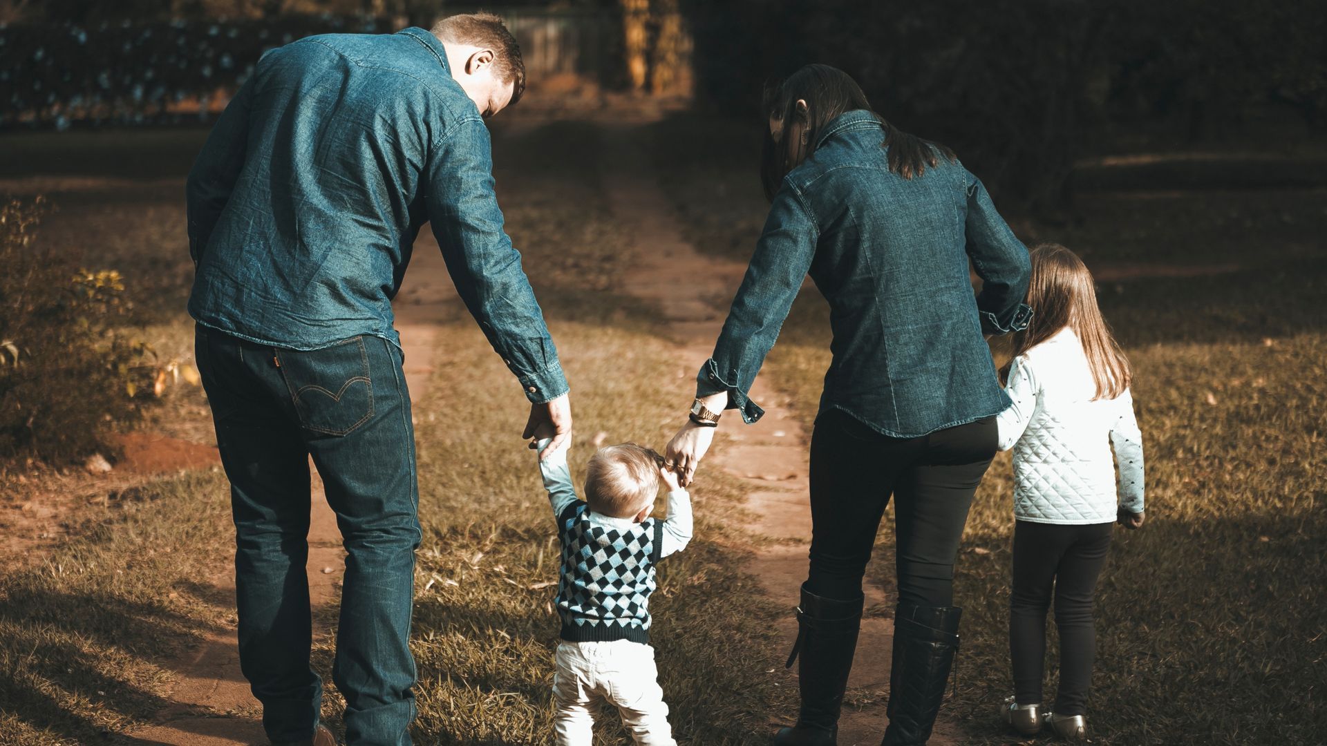 Family walking down a path, holding hands.