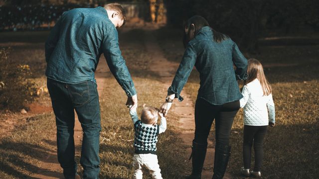 Family walking down a path, holding hands.