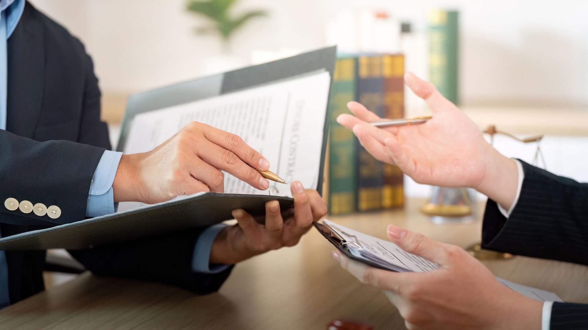 Two people reviewing documents in an office, one pointing at paper, the other gesturing.