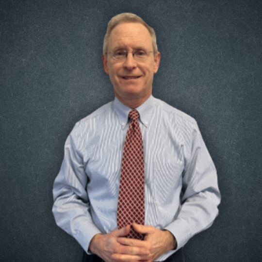 A man in a striped shirt and tie smiles for the camera