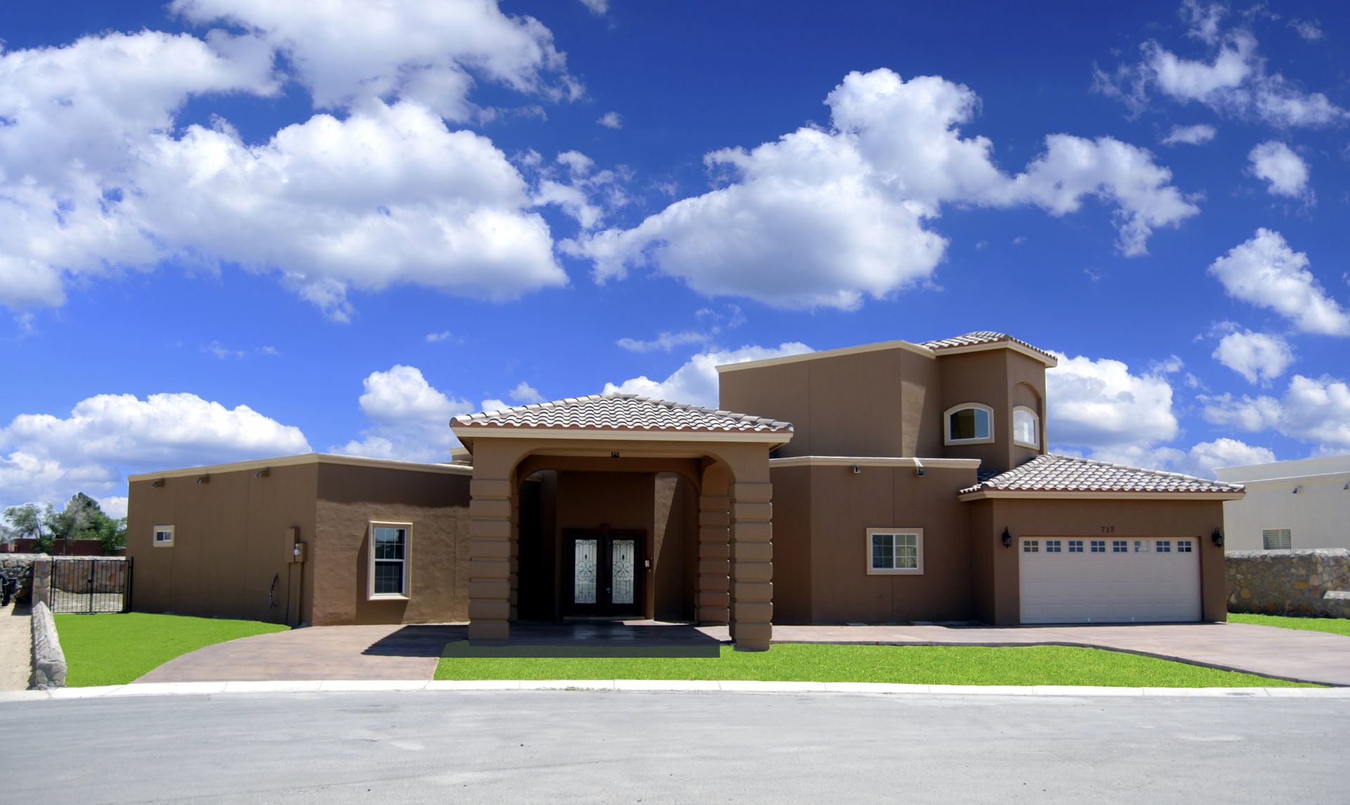 A large house with a blue sky and clouds behind it