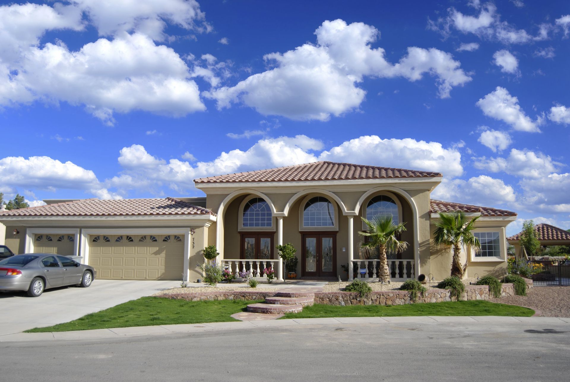 A large house with two cars parked in front of it