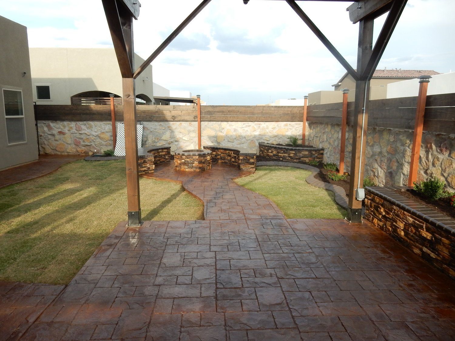 A backyard with a brick walkway and a stone wall