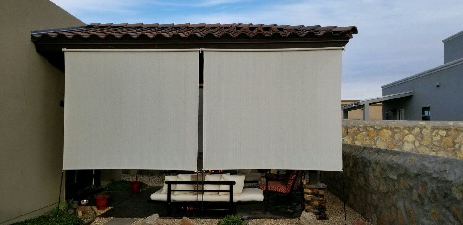 A white awning is covering a patio area with a table and chairs.