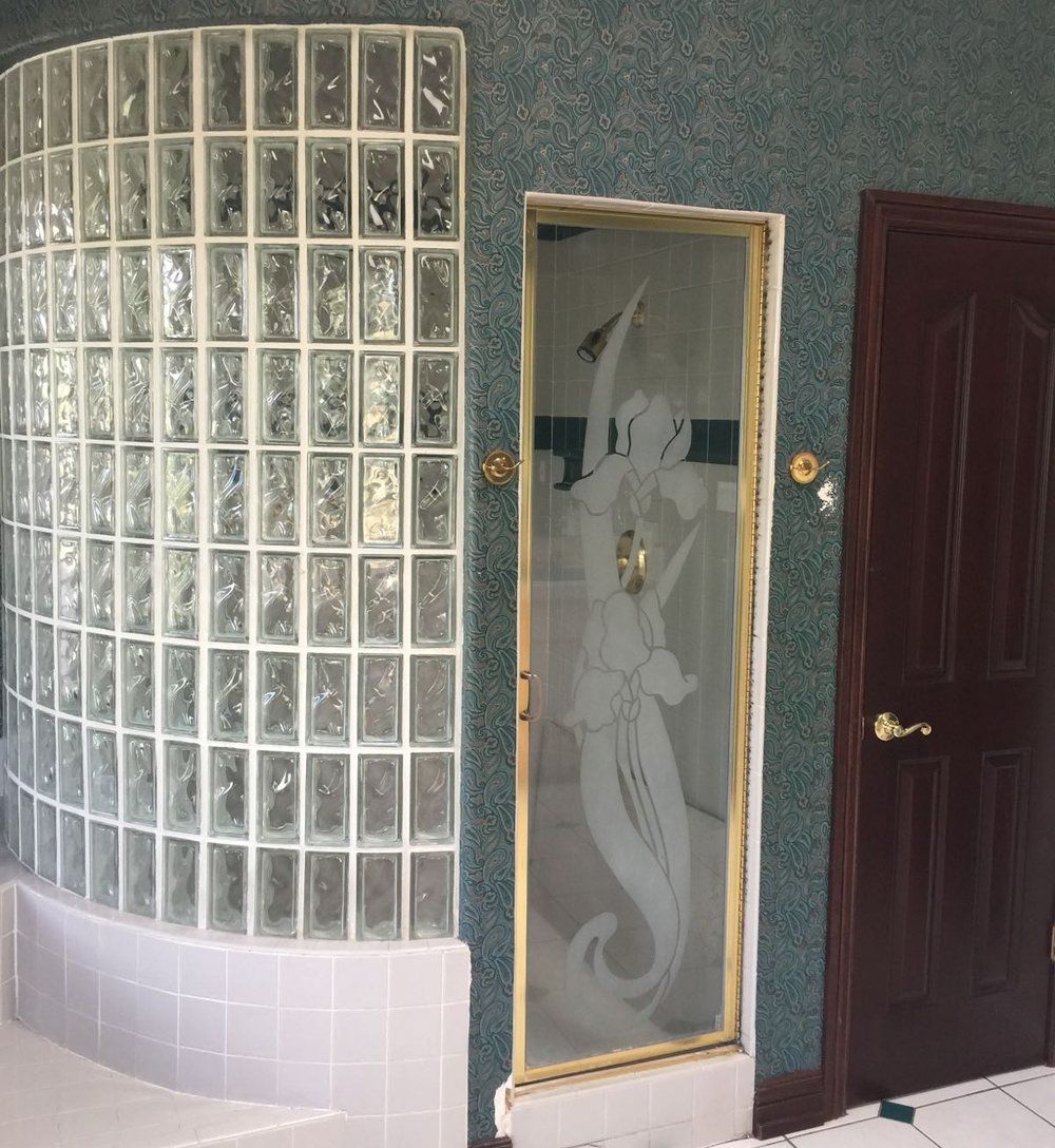 A bathroom with a glass block shower and a door