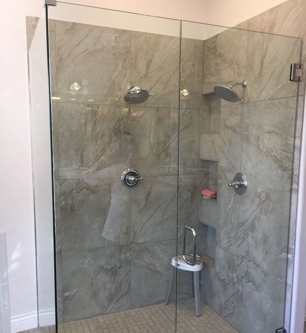 A bathroom with a walk in shower with a glass door.