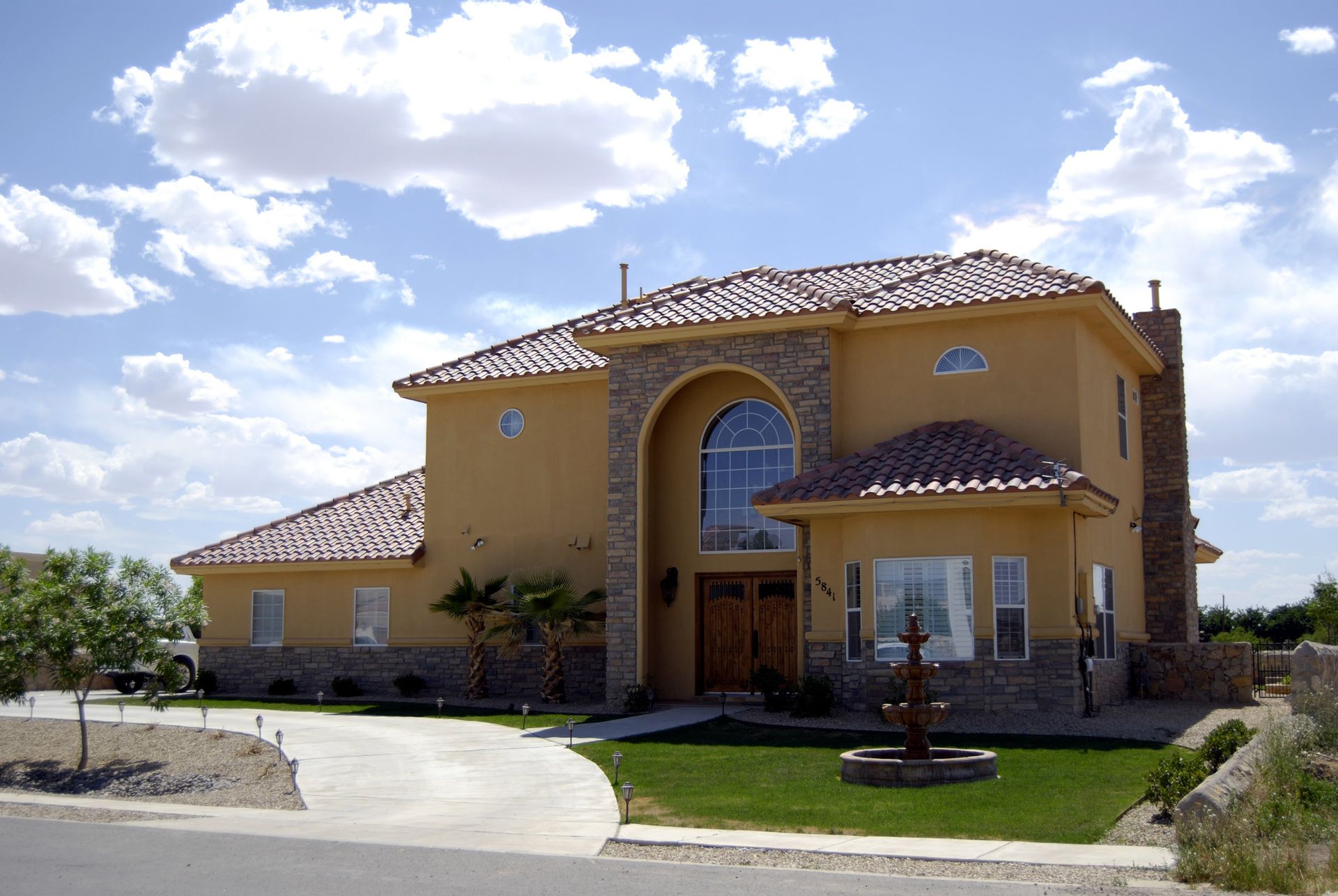 A large house with a tiled roof and a fountain in front of it
