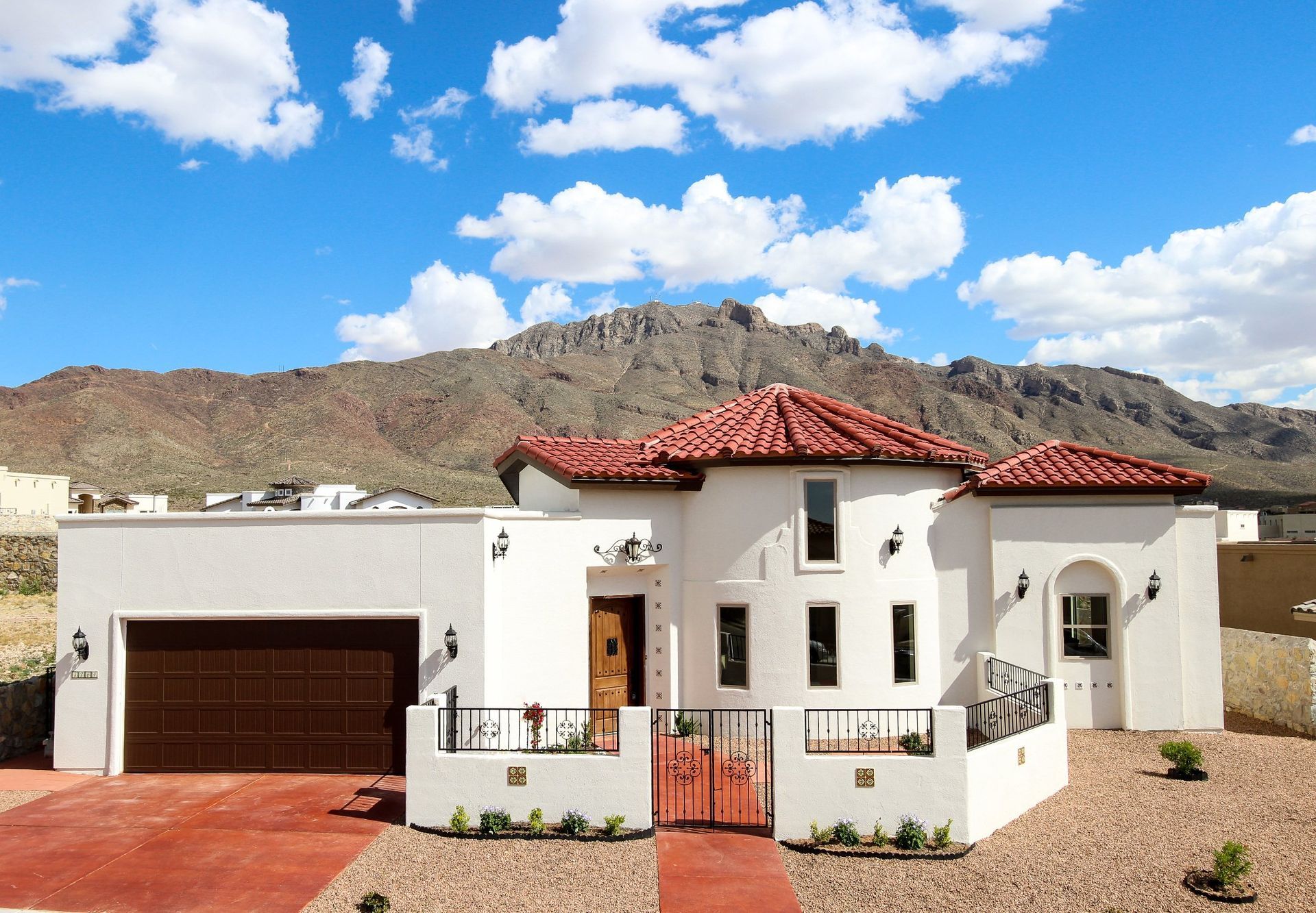 A white house with a red tile roof and mountains in the background