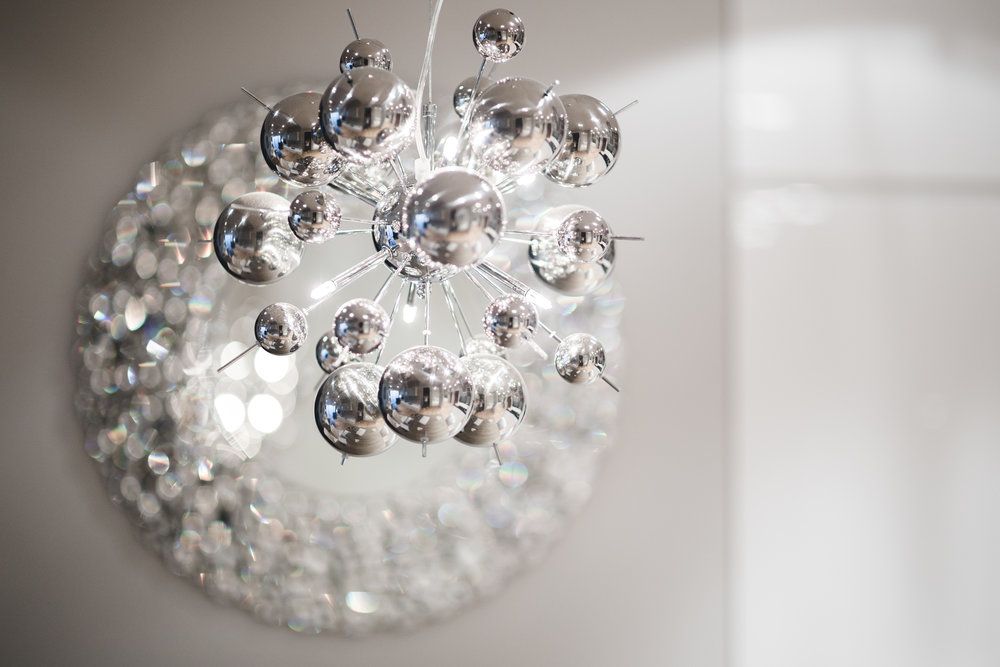 A silver chandelier is hanging from the ceiling next to a mirror.