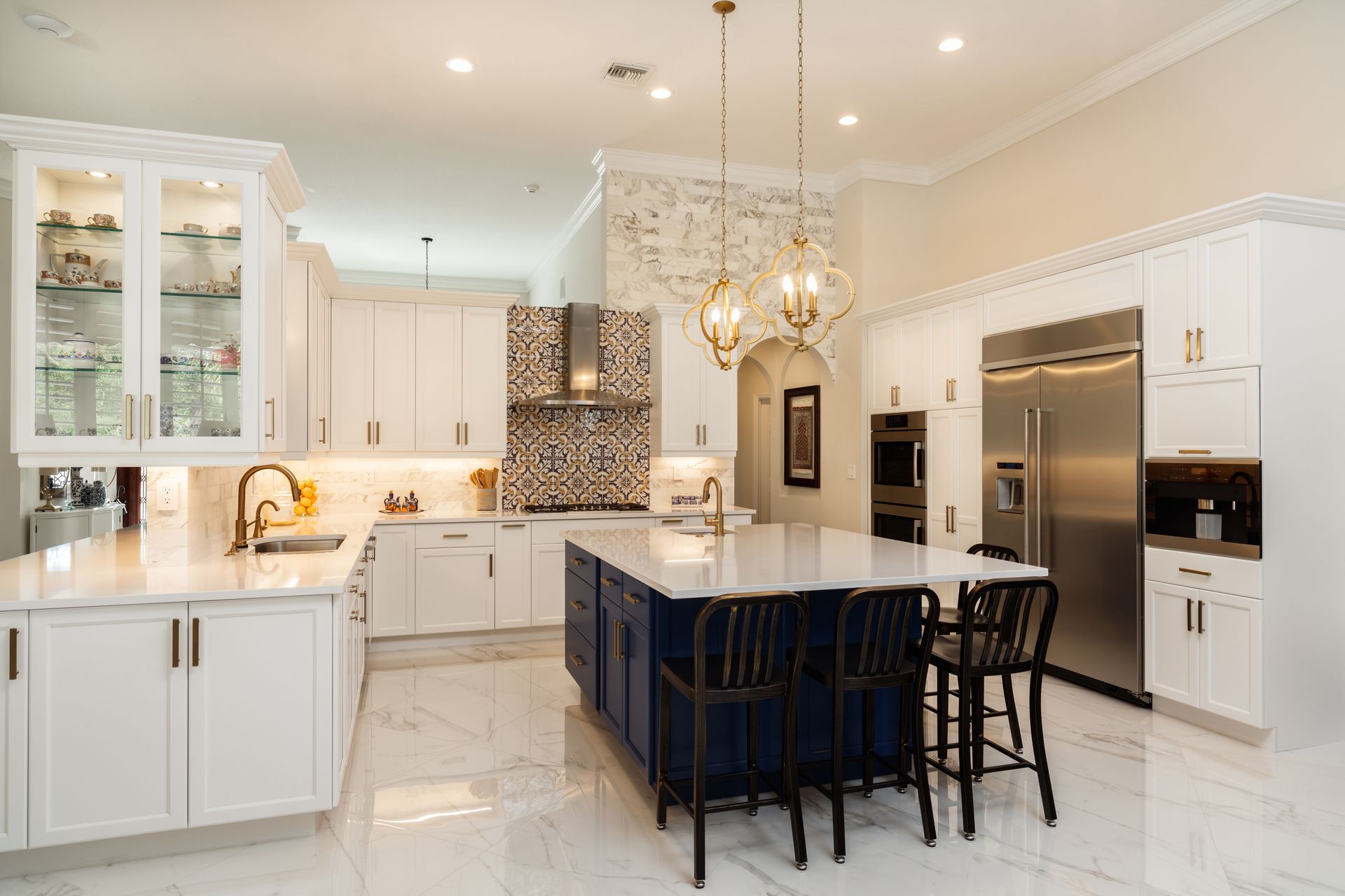 A large kitchen with white cabinets , stainless steel appliances , and a blue island.