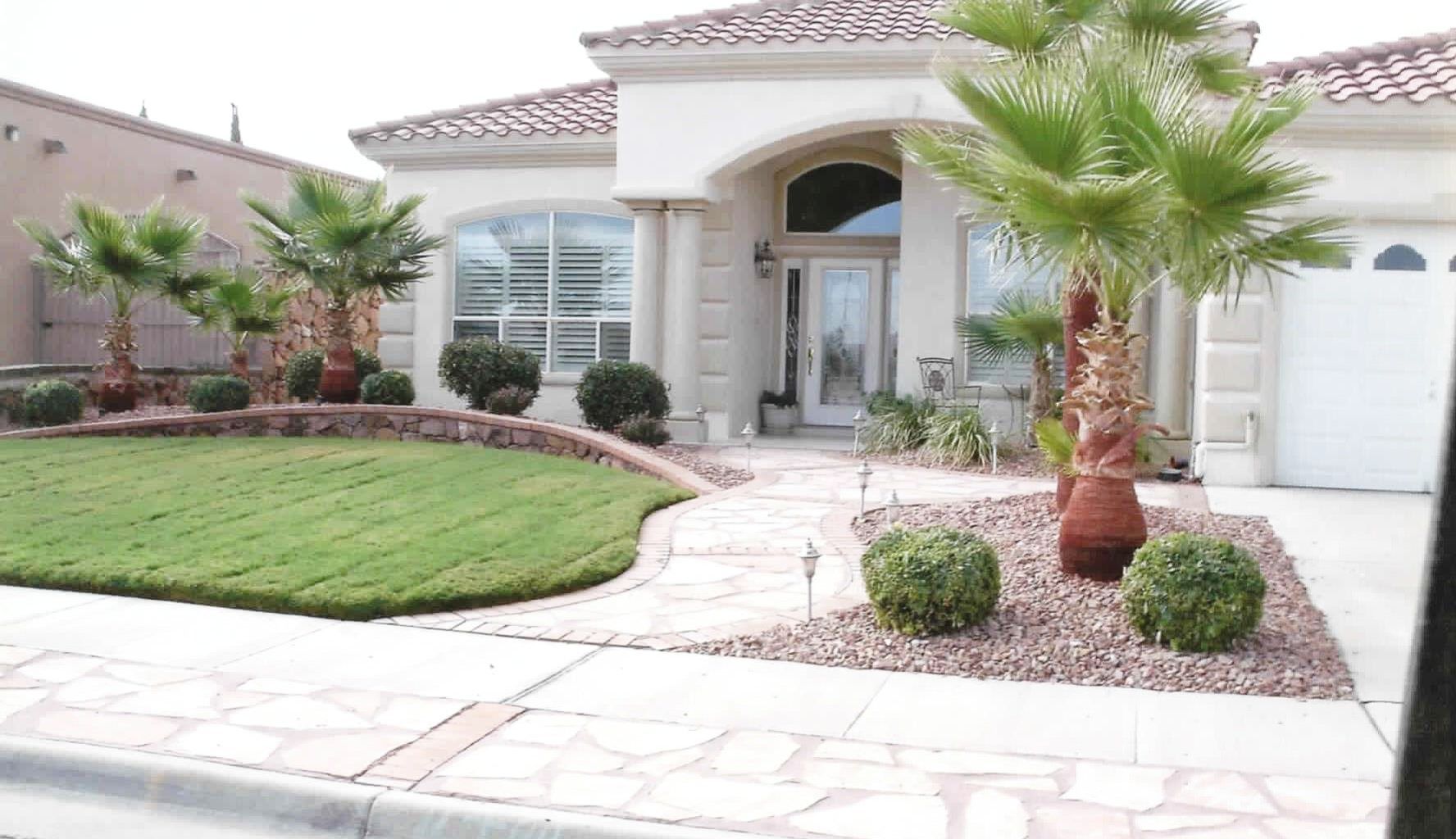 A house with a lush green lawn and palm trees in front of it.