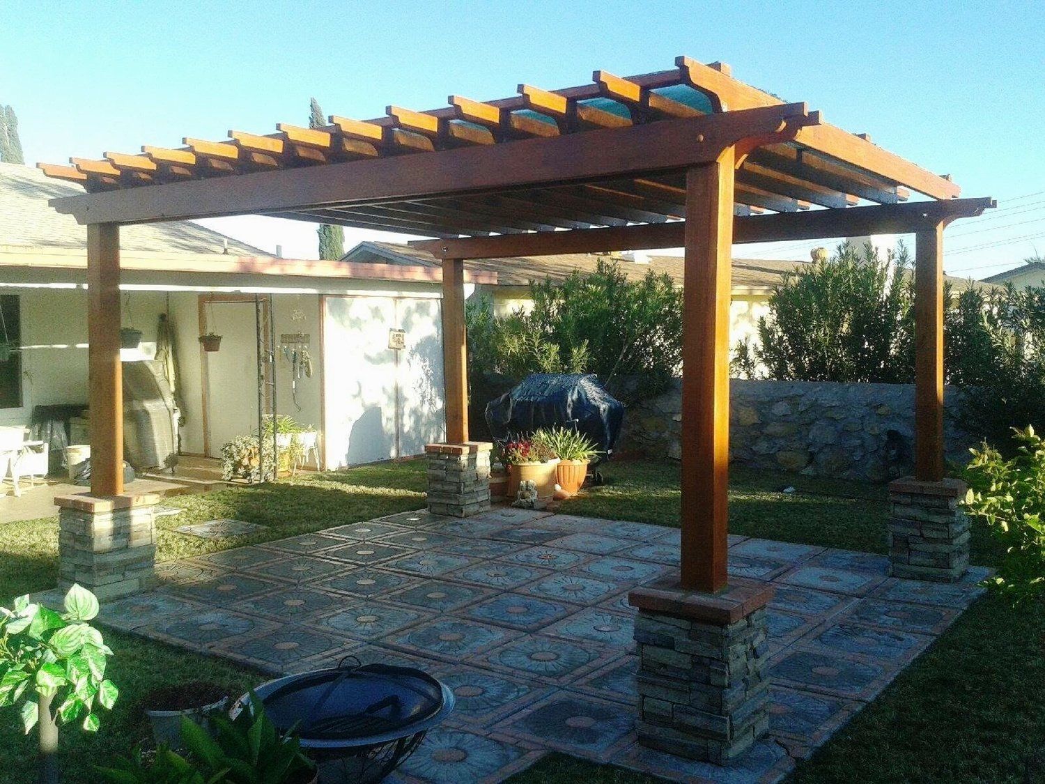 A wooden pergola is in the backyard of a house