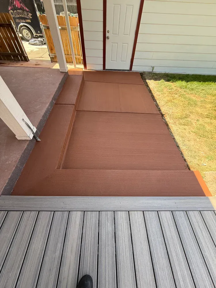 Steps leading up to a door. Brown steps bordered by gray decking.