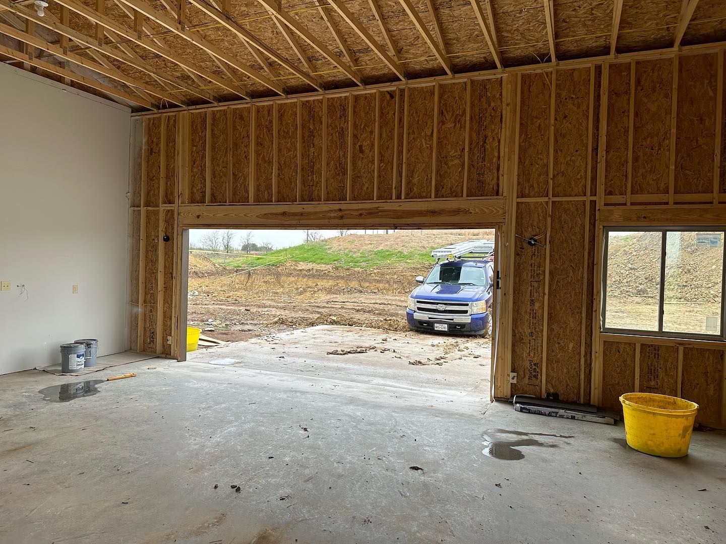 A blue van is parked in a garage under construction.