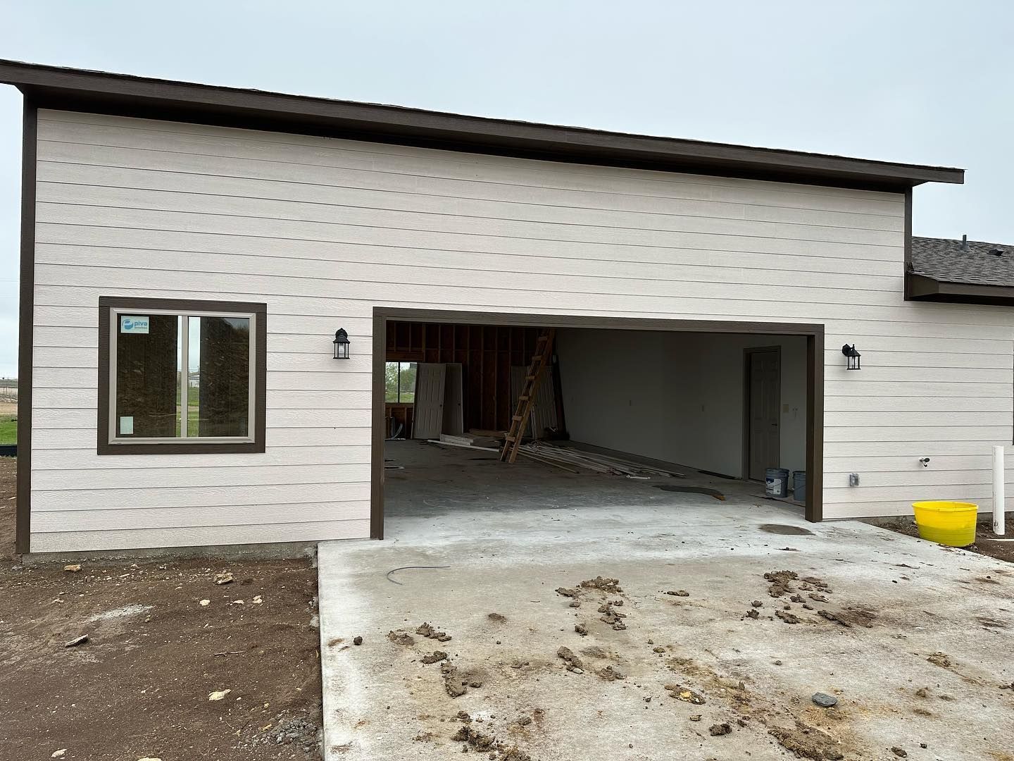 A house under construction with a garage and a window.