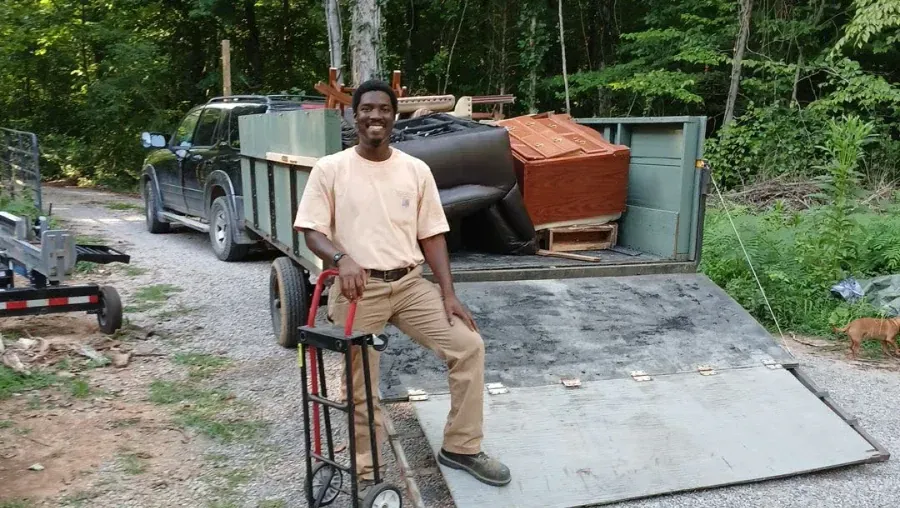 A man is standing next to a dolly in front of a truck.