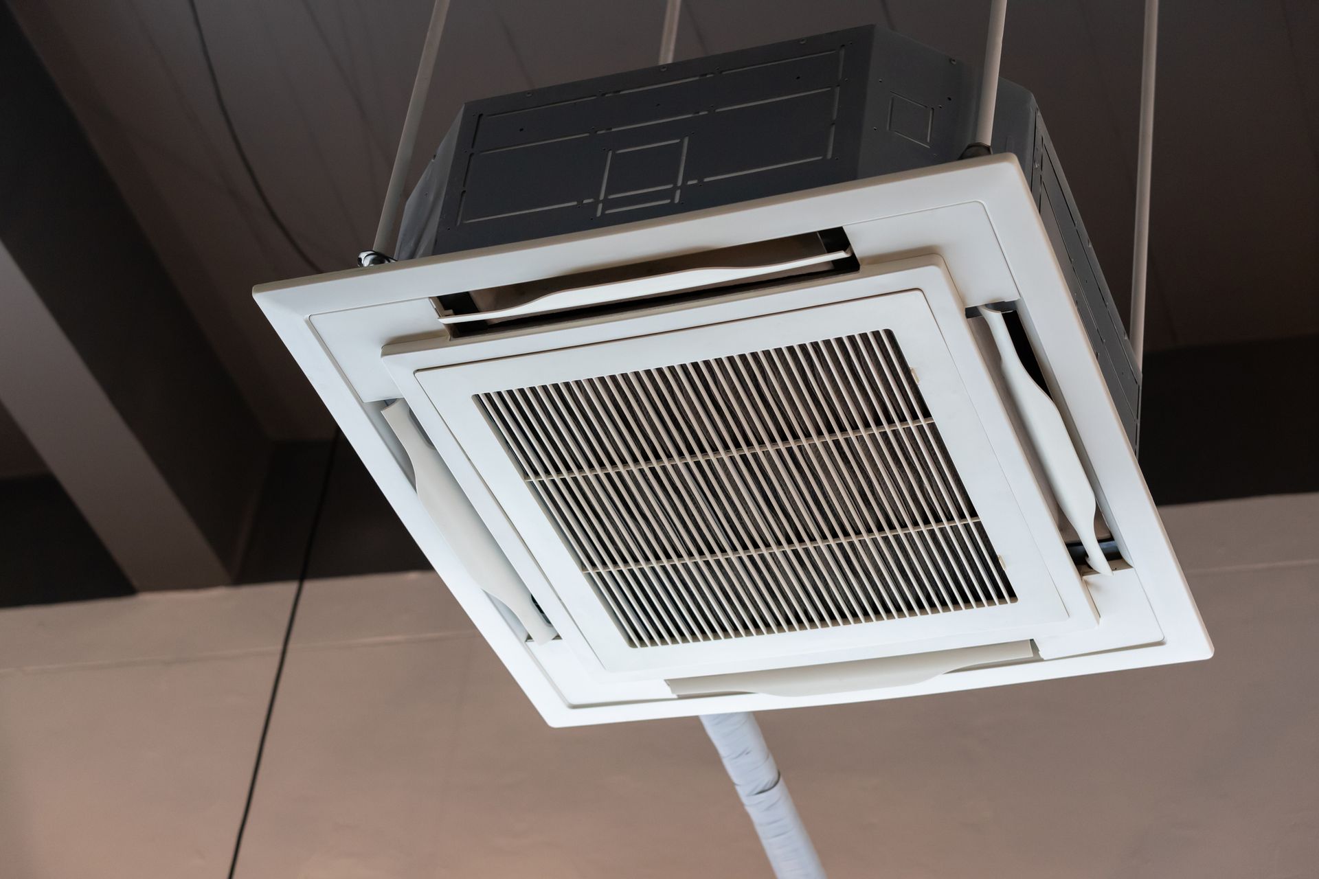 A ceiling mounted air conditioner is hanging from the ceiling.