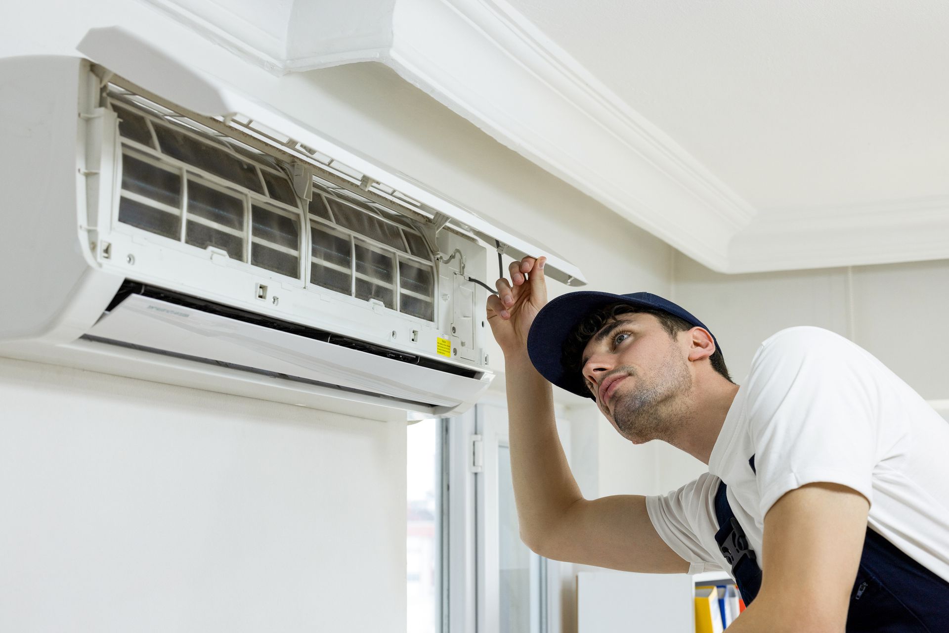 An air conditioning contractor technician repairing a central air conditioning system indoors.