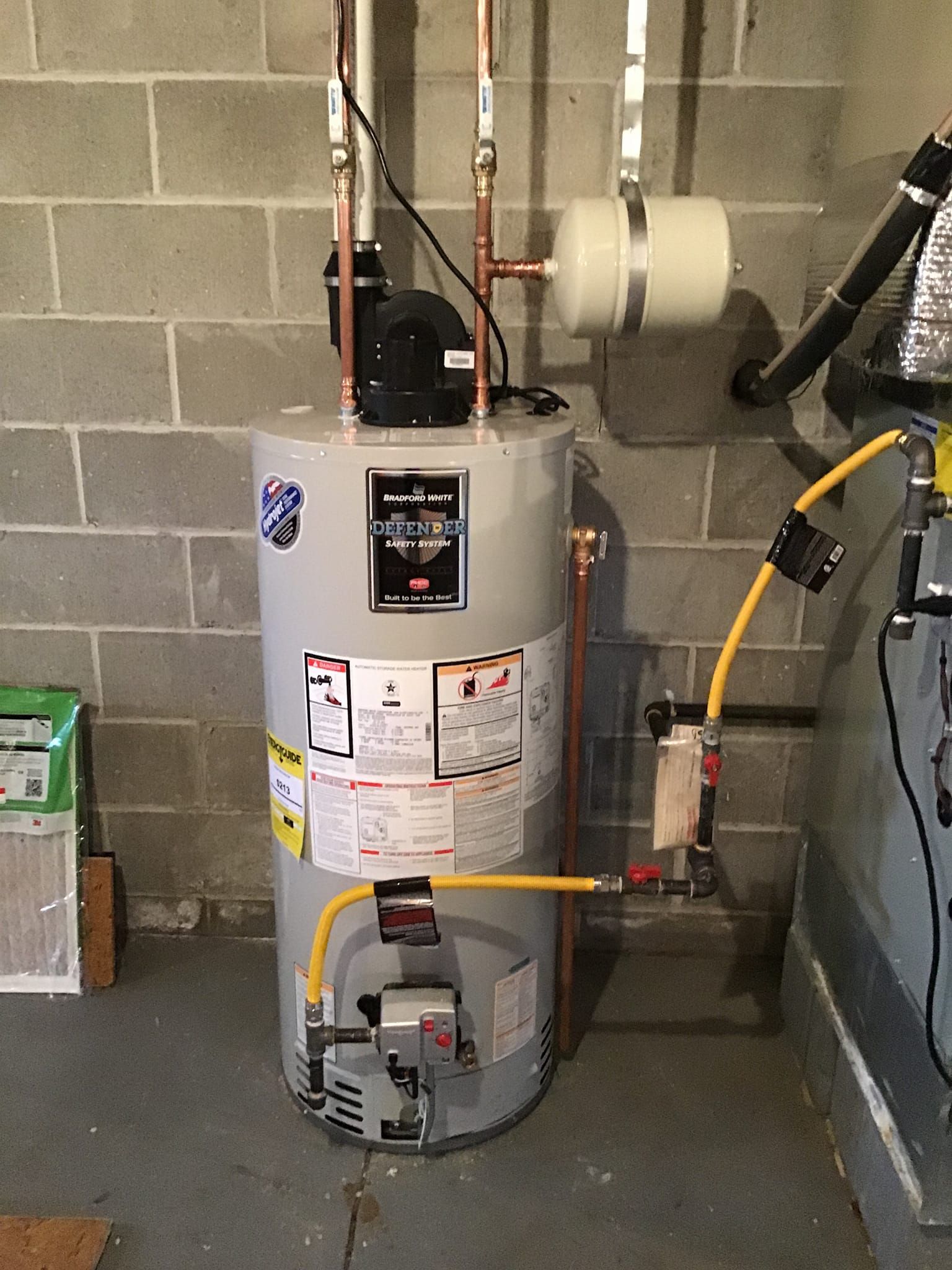 Two men are working on a boiler in a room.