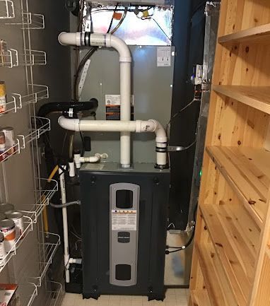 A gas heater is sitting in a pantry next to a wooden shelf.