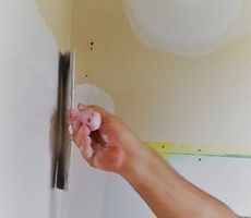 A person is plastering a wall with a trowel.