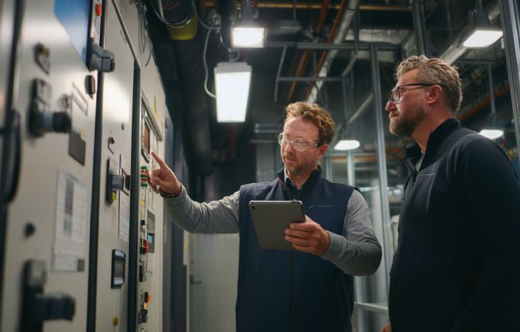 elevator consultant reviewing digital performance data on tablet inside mechanical control room
