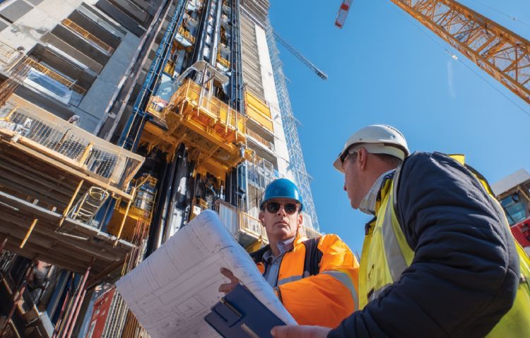 elevator consulting professional leading a client walkthrough of elevator installation plans on a construction site