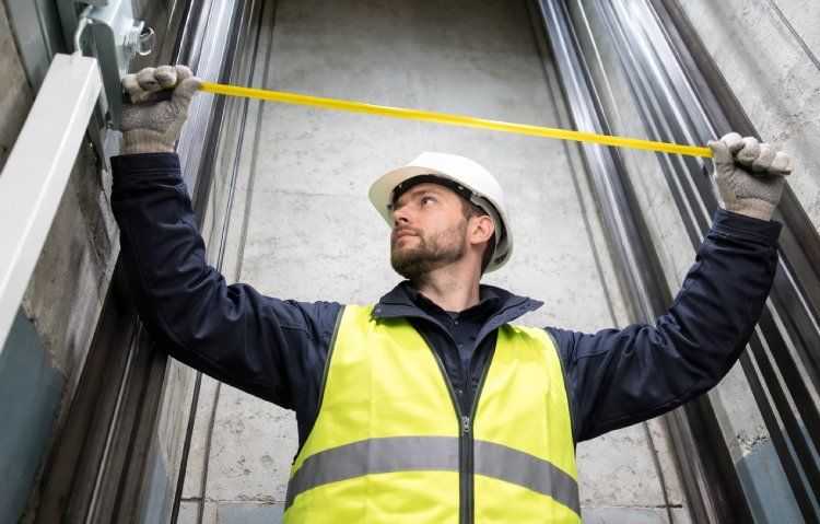 elevator technician measuring shaft dimensions