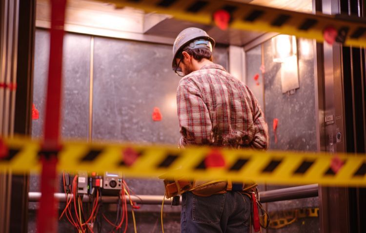 technician adjusting pressure sensors and acceleration monitor during elevator load test sequence