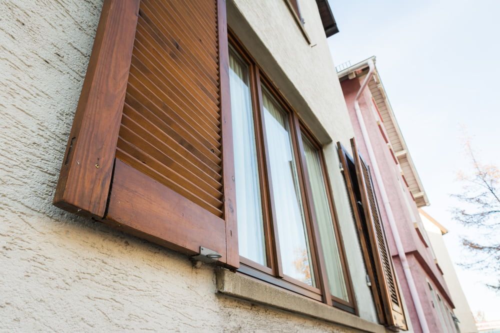 A Window With Wooden Shutters on the Side of a Building — Tully Blinds in Mission Beach, QLD