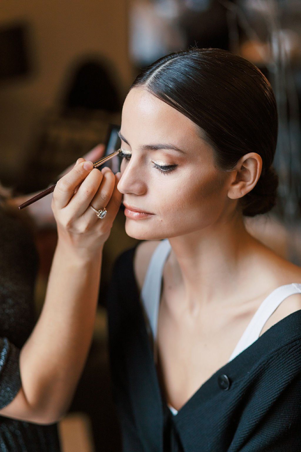 A woman is getting her makeup done by a makeup artist.