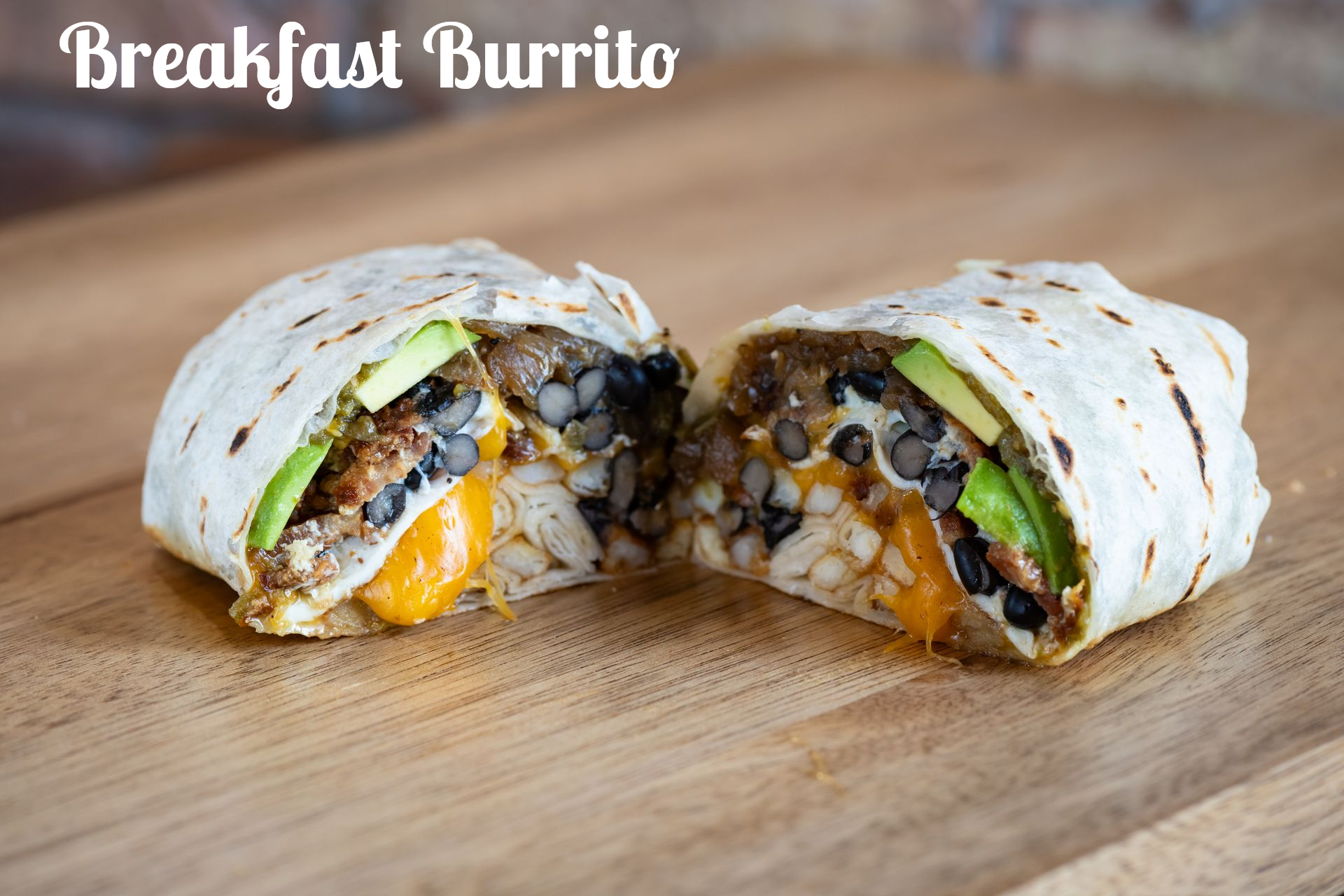 Breakfast burrito cut in half, revealing fillings including beans, cheese, and avocado.