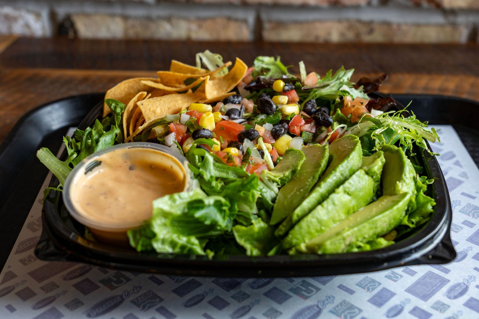 Salad with avocado, corn, black beans, chips, and dressing.