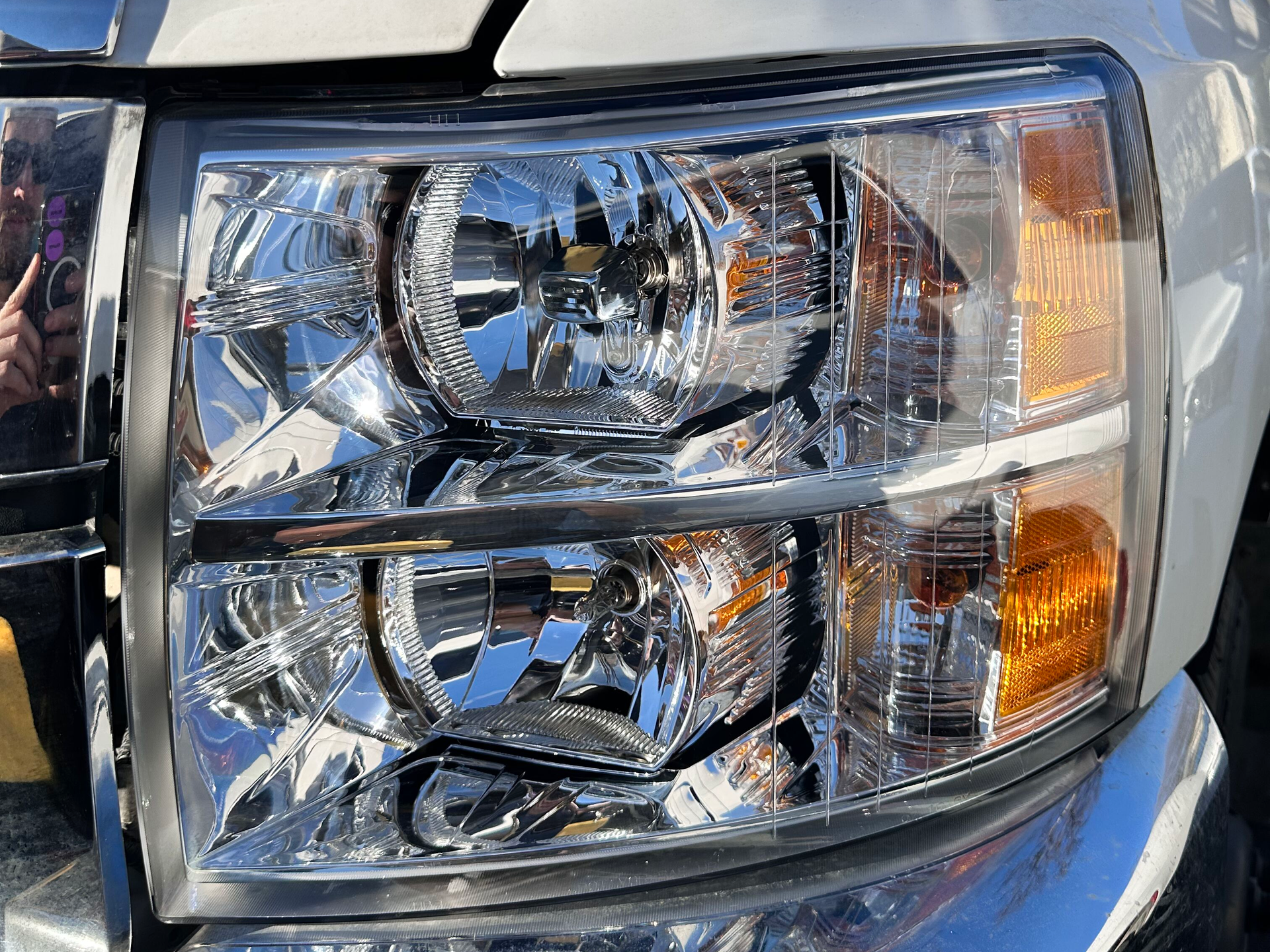 Close-up of a truck headlight with multiple reflective sections and orange side marker.