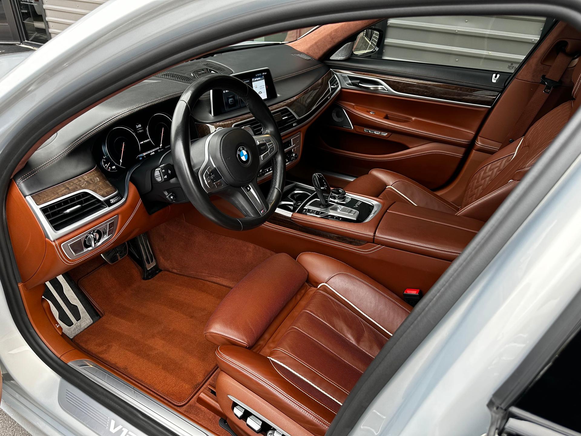 Brown leather interior of a luxury BMW with a silver exterior, including the steering wheel, seats, and dashboard.