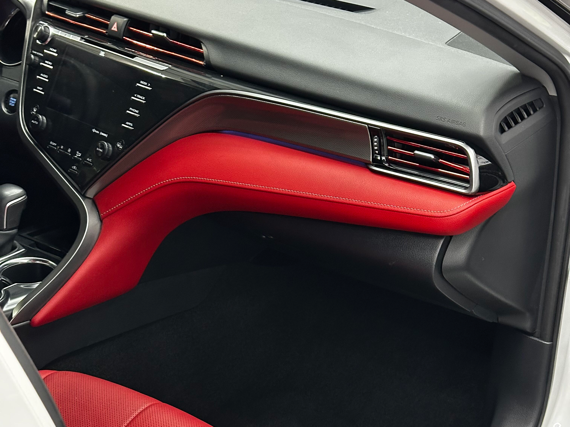 Red and black car dashboard detail. Red leather accents, air vent, and digital display are visible.