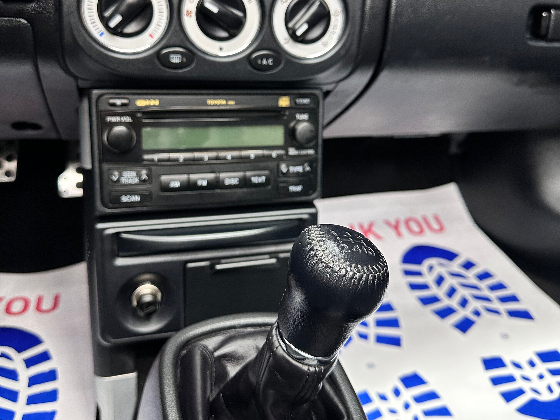 Interior of a car showing the dashboard with the radio, gear stick, and footwell.