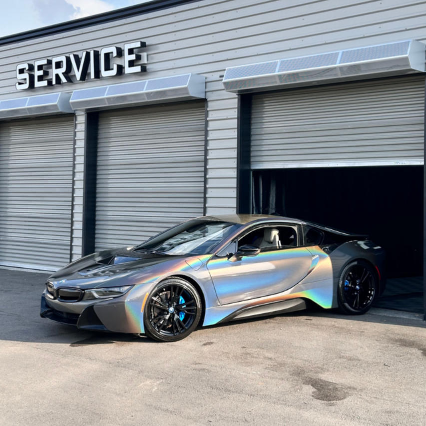 Red Lexus sports car in a brightly lit garage. It has a gray racing stripe and black wheels.