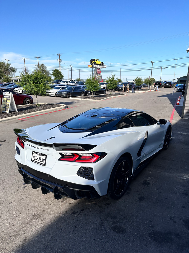 A iridescent BMW i8 coupe parked on a checkered floor. The car has black wheels and a dark hood.