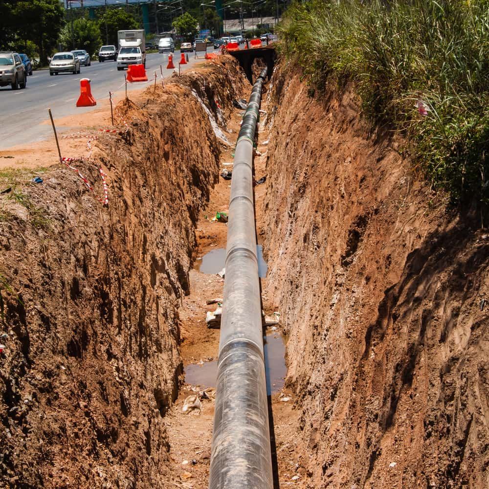 A Large Pipe is Being Installed in a Trench Next to a Road — Wards Group QLD in Wondai, QLD