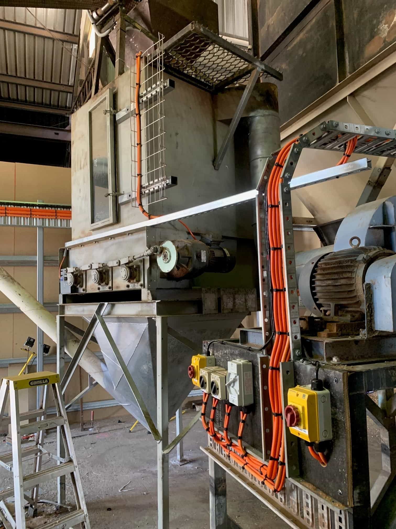 Industrial machine with electrical wiring, metal structure, and hopper.