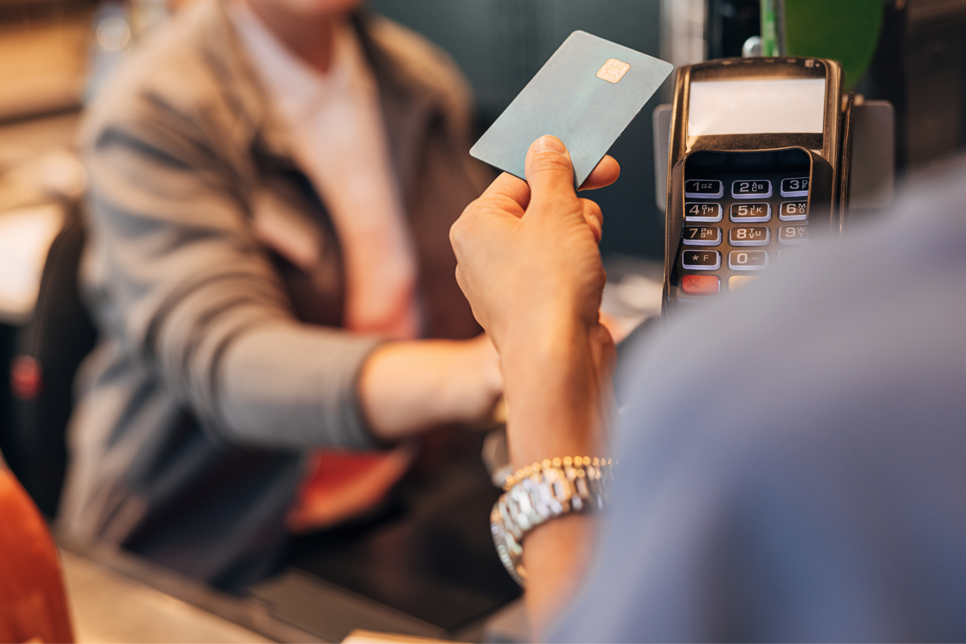 A customer pays for a purchase by holding a blue credit card over a card payment terminal at a checkout counter.