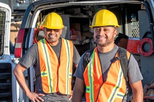 Two men are working on a meter on the side of a house.