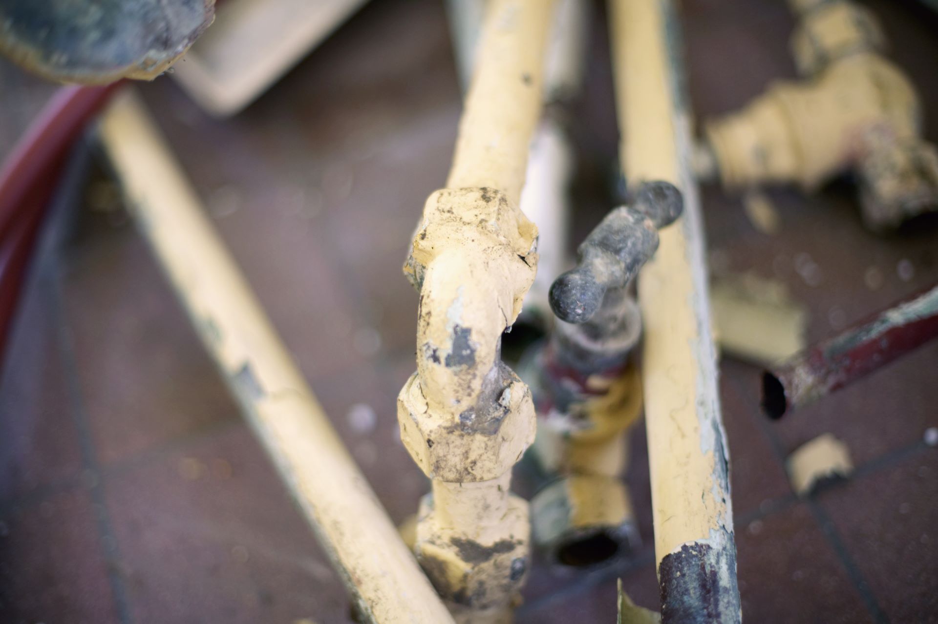 Close-up of old, broken yellow-painted metal pipes and fittings.