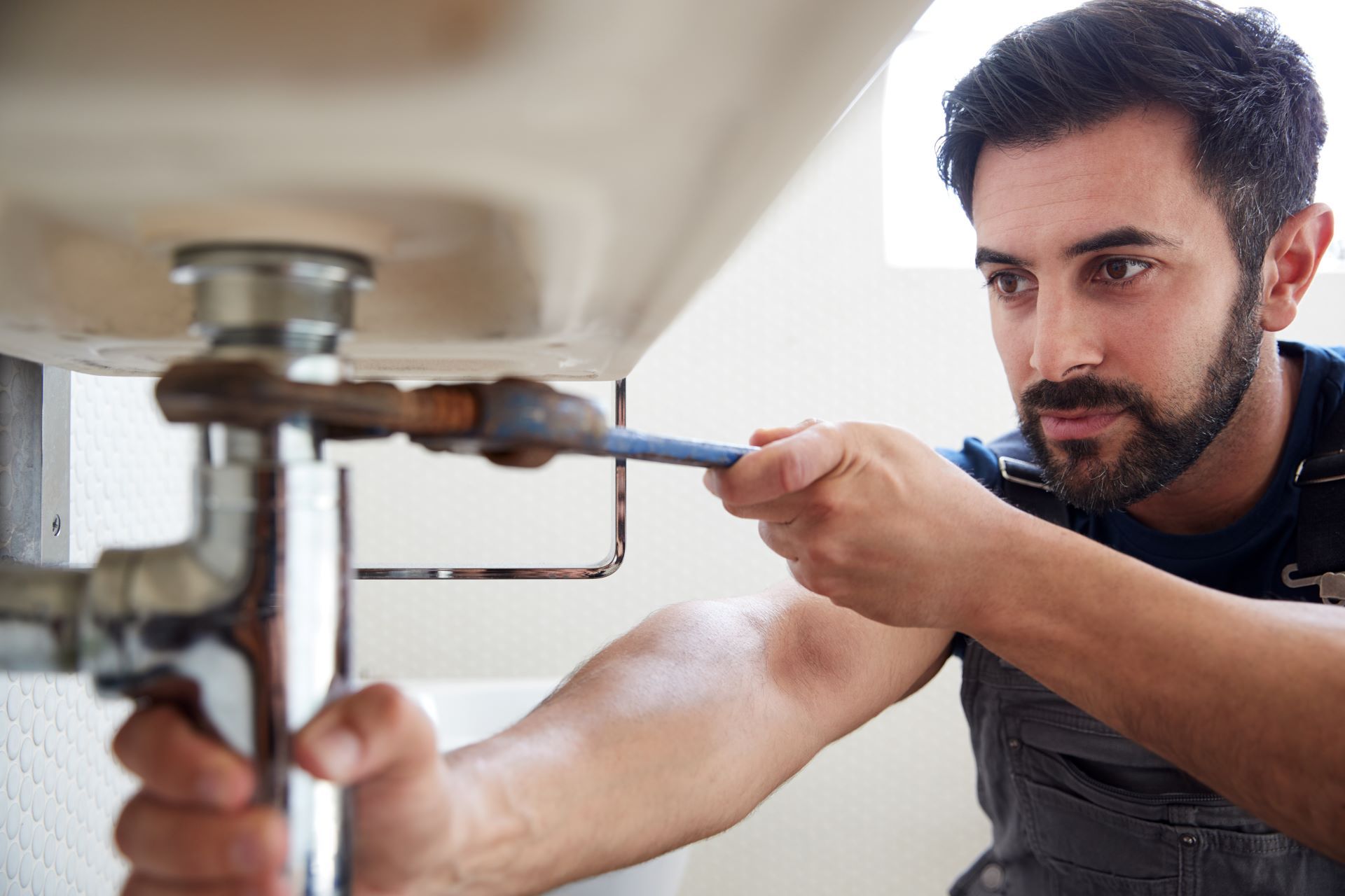 Plumber using a wrench under a sink.