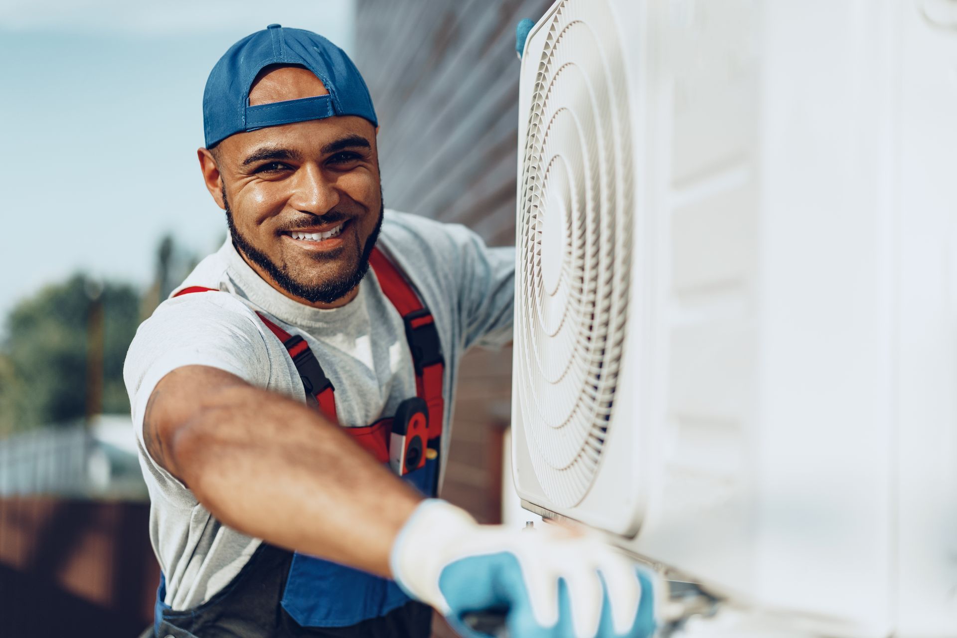 Technician smiling while cleaning an outdoor air conditioning unit with a cloth