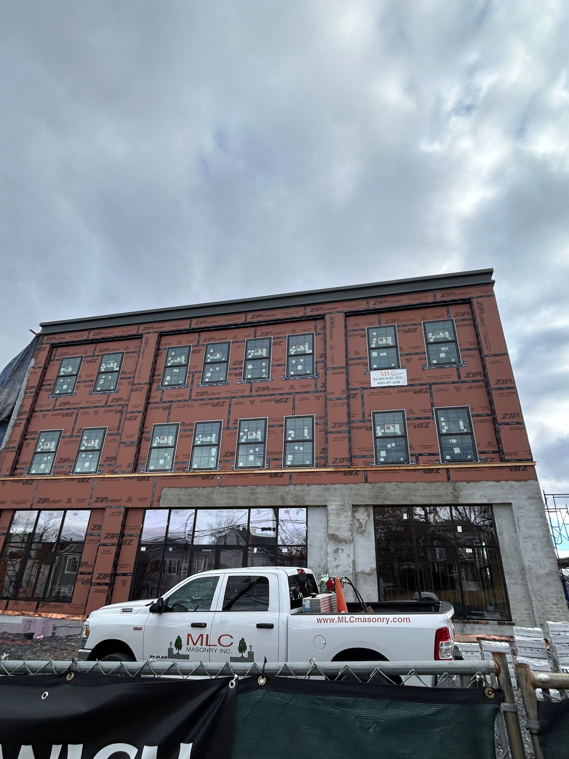 A white truck is parked in front of a large brick building