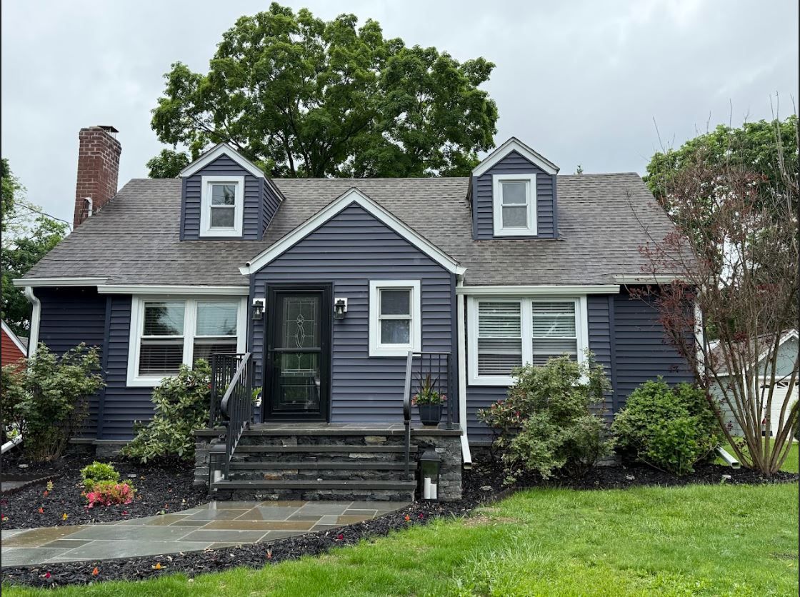 A blue house with white trim and a gray roof