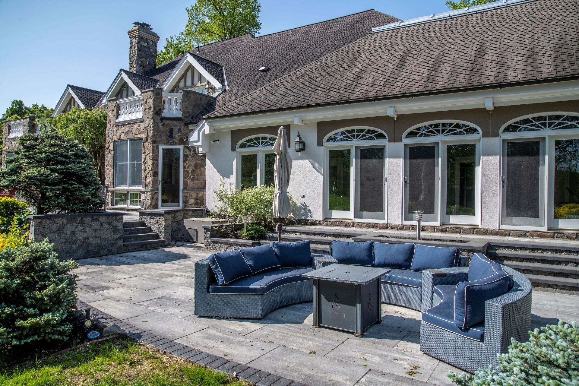 A large house with a patio with a couch and chairs in front of it.