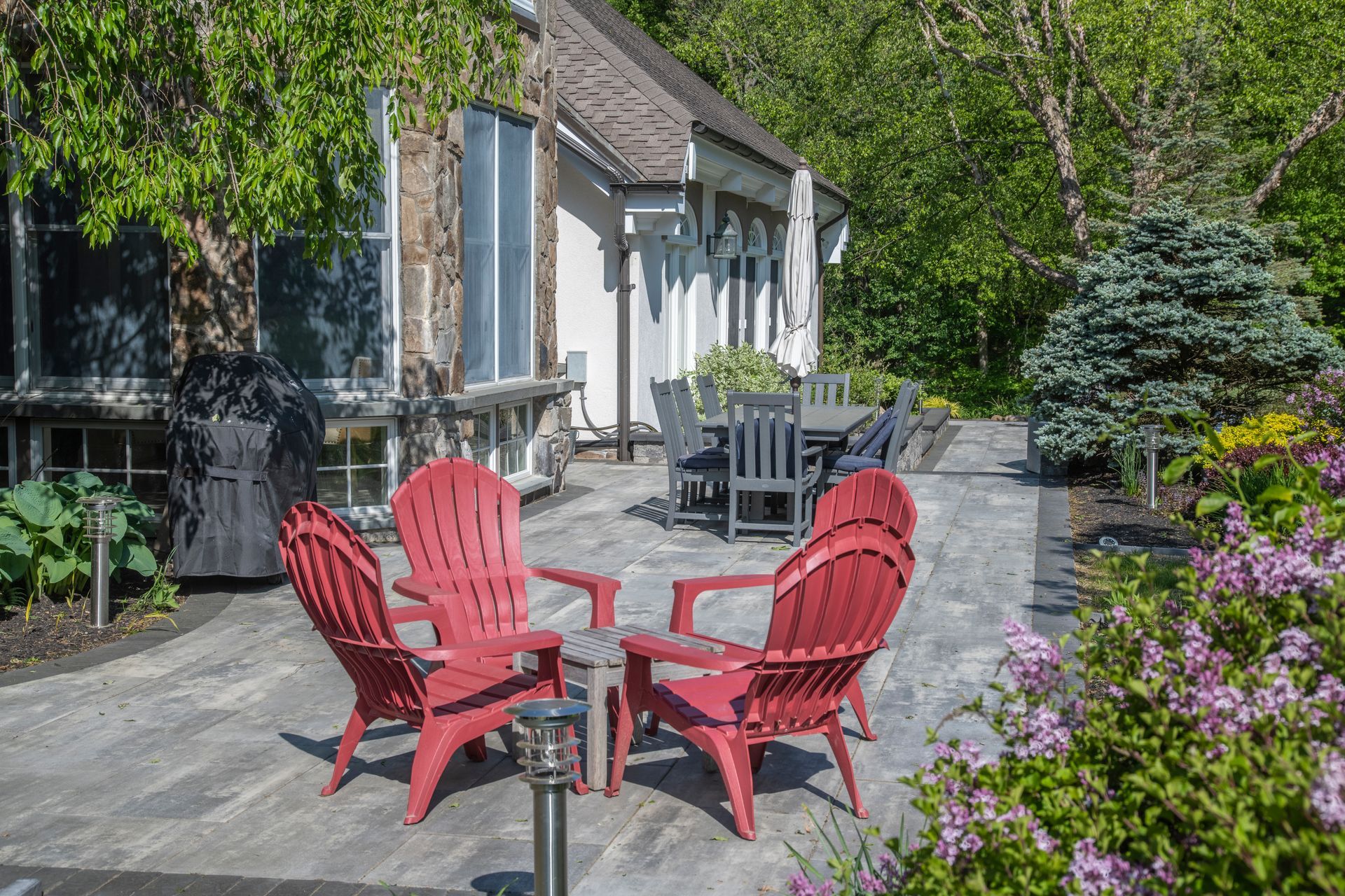 A patio with red chairs and a table in front of a house.